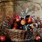 Cesto in vimini con melograni, bacche autunnali e aster.
